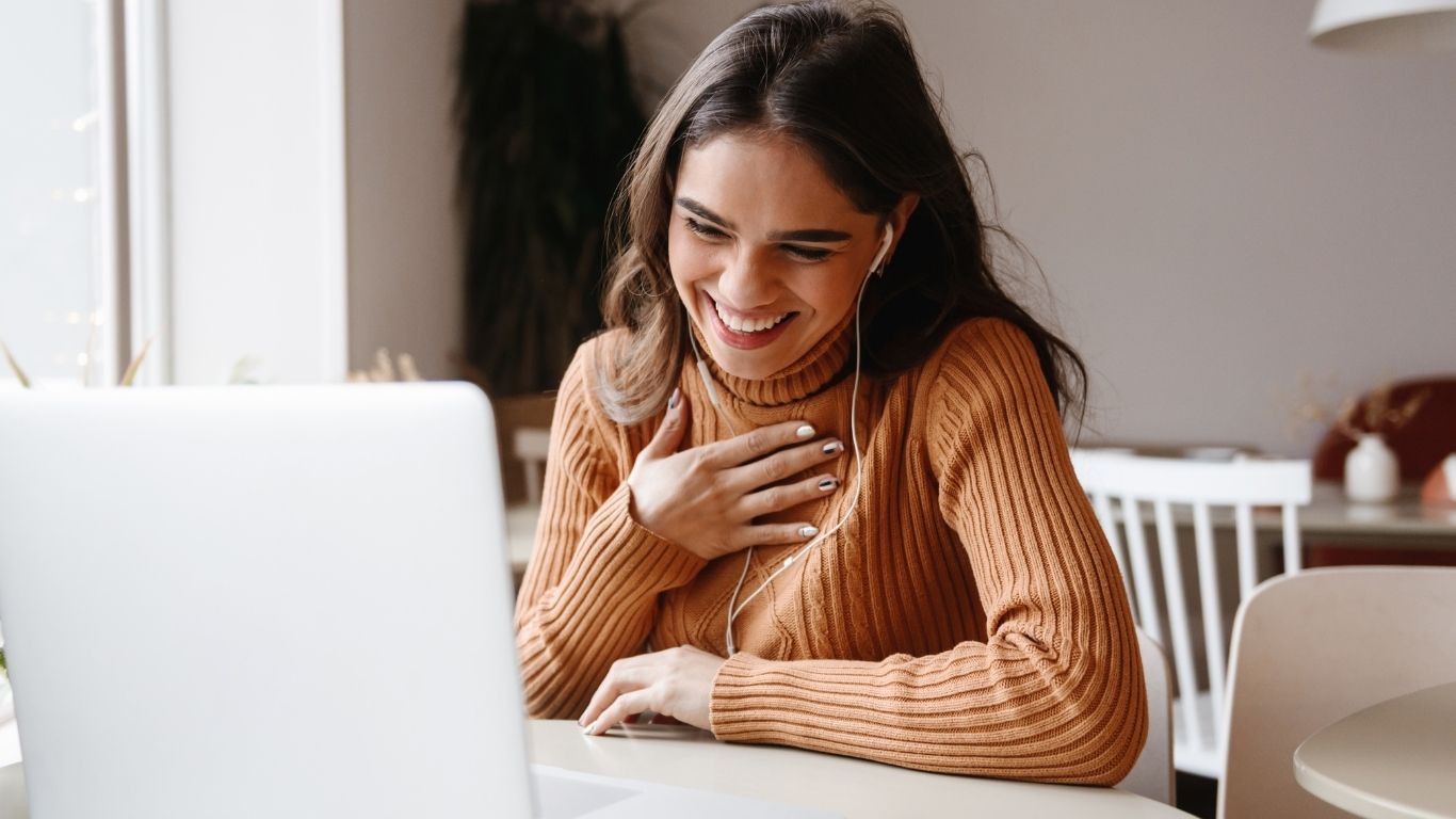Woman client in virtual call with Scott E. Burgess during the 30-Day Intensive, touching chest with emotional relief from daily guidance and support.