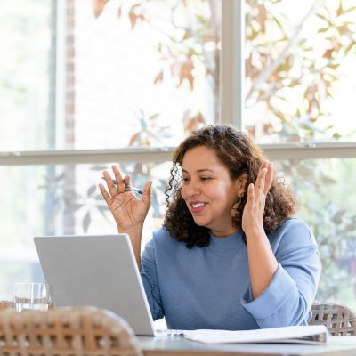 Woman client in virtual call with Scott E. Burgess during the 30-Day Intensive, hands engaged while speaking with notepad nearby, enjoying daily guidance.