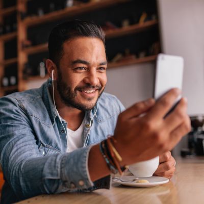 Man in virtual call with Scott E. Burgess during the 30-Day Intensive, engaged in conversation at a coffee shop with earbuds and daily guidance.