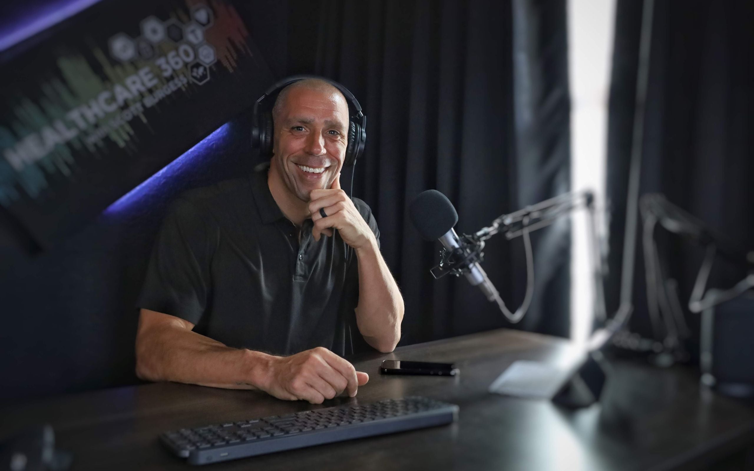 Scott E. Burgess podcast guest smiling at podcast table, sharing engaging conversations on natural healing, functional mushrooms, and performance.