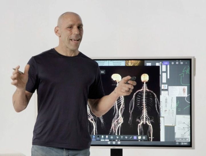 Scott E. Burgess speaking at a corporate event with skeleton model behind him, teaching executives about health, resilience, and human performance.